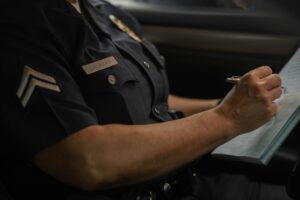 A Corpus Christi Police officer named Salazar writes in a notebook while seated in a patrol car, focused on documentation duties.