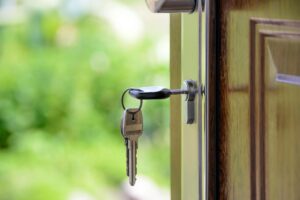 Corpus Christi pauses workforce: A close-up of a key inserted in a door lock with a blurred green outdoor background, symbolizing access to housing or homeownership.