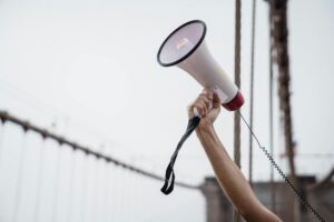 A raised hand holds a megaphone during a protest, symbolizing public voice as Corpus Christi rallies against immigration detentions.