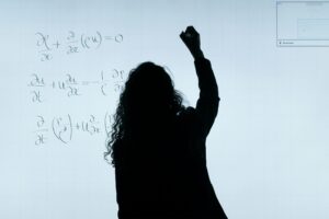 The teacher writes complex equations on a digital whiteboard in a classroom at Gregory-Portland ISD, highlighting a STEM education focus.