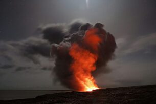 Fiery explosion lights up the night sky with thick black smoke rising, symbolizing chaos after Trump Orders Iran Strikes.