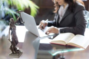 Texas Rises in ICE Partnerships: Lady Justice statue on desk with a lawyer working on a laptop beside an open legal book in an office.