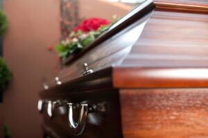 Close-up of a polished wooden casket adorned with flowers during a funeral service — Remembering Blake Farenthold.