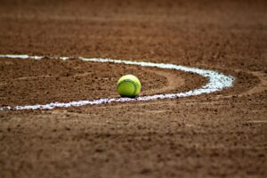Yellow softball rests on the dirt field near the foul line at Whataburger Field; London Pirates honored by Hooks.