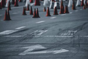 Traffic cones line a city street under repair with faded lane markings and arrows, as Corpus Christi reconsiders street maintenance funding.
