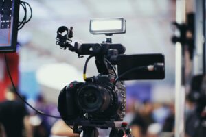KEDT Faces Uncertain Future as a professional Canon EOS video camera with lighting gear captures footage in a blurred studio or event setting.