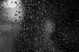 Raindrops cling to a window pane, casting a somber, reflective mood. A reminder of Baffin Bay's Future and climate's effect.