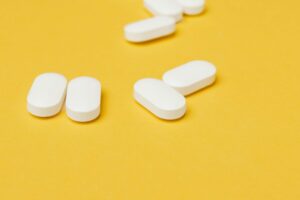 White pills scattered on a yellow surface, symbolizing opioid use and overdose risks as Narcan Vending Machine Launches in Corpus Christi.