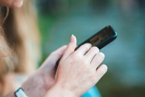 Person using a smartphone to browse social media, symbolizing online threats in the Threat Against Corpus Christi case.