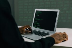 Person working on a laptop displaying green code on a dark screen in a dim room — City Attorney Alleges Fraud.