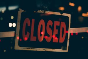 Closed sign displayed on a storefront window during Corpus Christi Columbus Day, symbolizing federal holiday closures.