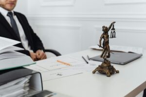Judge Drops Charges: A lawyer sits at a desk with legal papers, a laptop, and a Lady Justice statue symbolizing law and fairness.