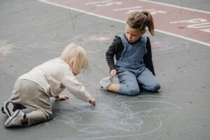 Two young children draw colorful chalk art on a playground surface — New Playground Planned in Corpus Christi.