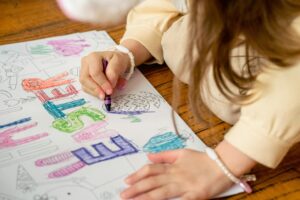 A child colors Easter-themed letters with crayons on paper, symbolizing creativity and learning as Texas student turns dyslexia.