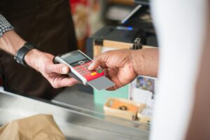 Where Corpus Christi Locals pay with a card at checkout, entering a PIN on a payment terminal held by a store cashier.