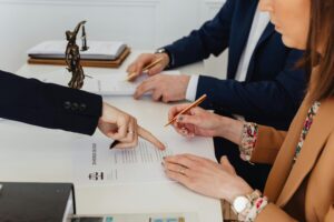 People reviewing legal documents at a table as hands point to details, symbolizing discussions on agreements tied to TIRZ 3 funding.