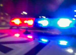 Blurred red and blue police lights flashing at night, symbolizing an active law enforcement response and public safety alert.