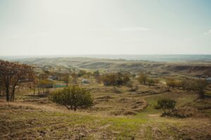 Rolling hills and undeveloped rural land with scattered trees and small structures, illustrating potential future development in a South Texas area.