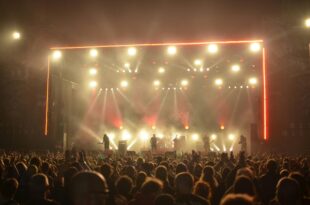 Crowd gathers at an outdoor stage during Buc Days rodeo as lights shine, promoting the Marshall Tucker Band concert on May 5
