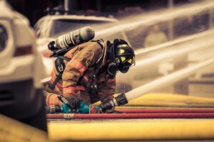 Firefighter kneels operating hose during Corpus Christi house fire response at night scene