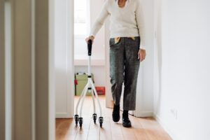Senior woman walking indoors with mobility cane walker, highlighting fall prevention and Elderly Safety at home.