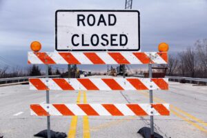 Road closed barricade blocking highway during for harbor bridge demolition with construction equipment ahead.