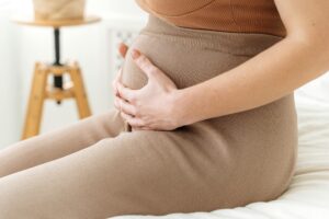 Close-up of a pregnant person holding their belly while sitting. Focus on maternity care. Trump Concentrates Pregnant.