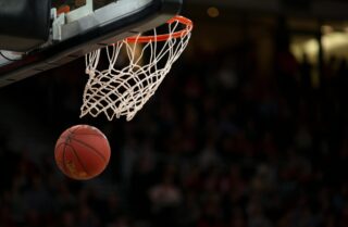 Basketball going through hoop during game with blurred crowd background, symbolizing Prairie View A&M basketball NCAA moment