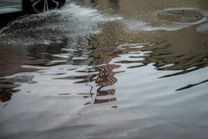 Georgetown flooding causes street water buildup as a vehicle drives through standing water after heavy rainfall.
