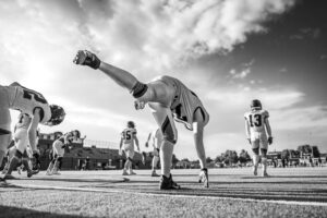 High school football players warm up on the field as Colton Nussmeier faces transfer eligibility uncertainty.