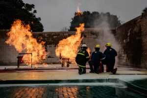 Corpus Christi firefighter camp trainees practice fire suppression during a live-fire emergency response exercise.