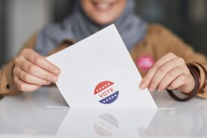 Voter places a ballot marked Vote into a box, representing local civic participation in the upcoming Corpus Christi election.