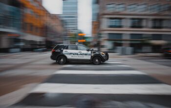 Police SUV travels through the blurred city street, illustrating the search for Steven Ramos missing in Corpus Christi, Texas.