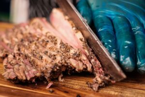 Texas barbecue beef prices rise as sliced smoked brisket is prepared on a wooden cutting board.