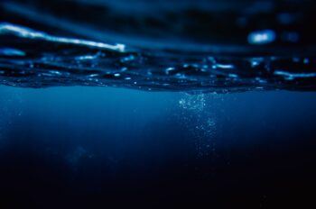 Dark blue underwater scene beneath the ocean surface representing the USS City of Corpus Christi memorial and submarine legacy.