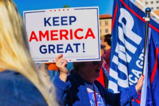 Donald Trump Corpus Christi rally supporters holding a “Keep America Great” sign and Republican campaign flags.