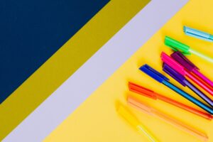 Colorful markers on a yellow background, representing creativity and a free writing workshop Corpus Christi for teens.